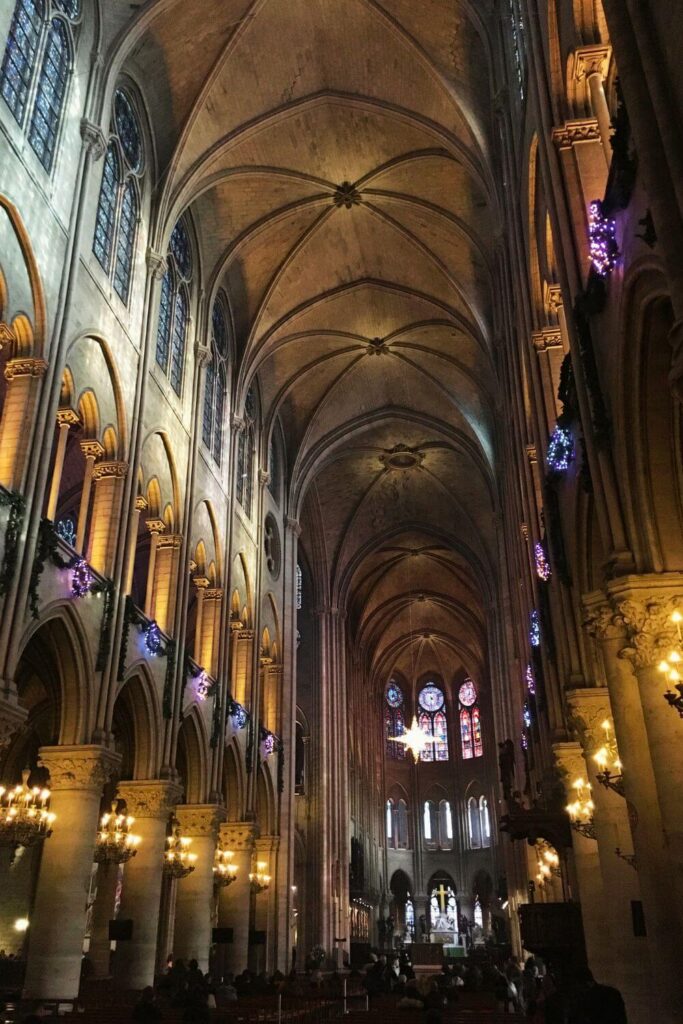 The interior of the notre dame cathedral in Paris with lots of gothic architecture and lovely lighting