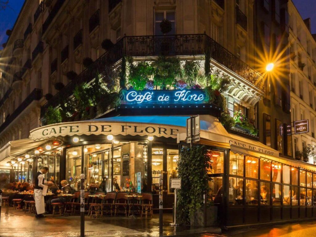 Cafe de Flores in Paris lit up at night with flower above the entrance