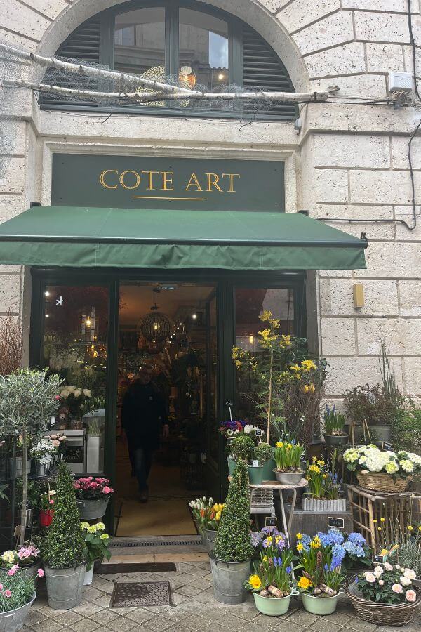 The outside of a flower shop in France with displays of flowers