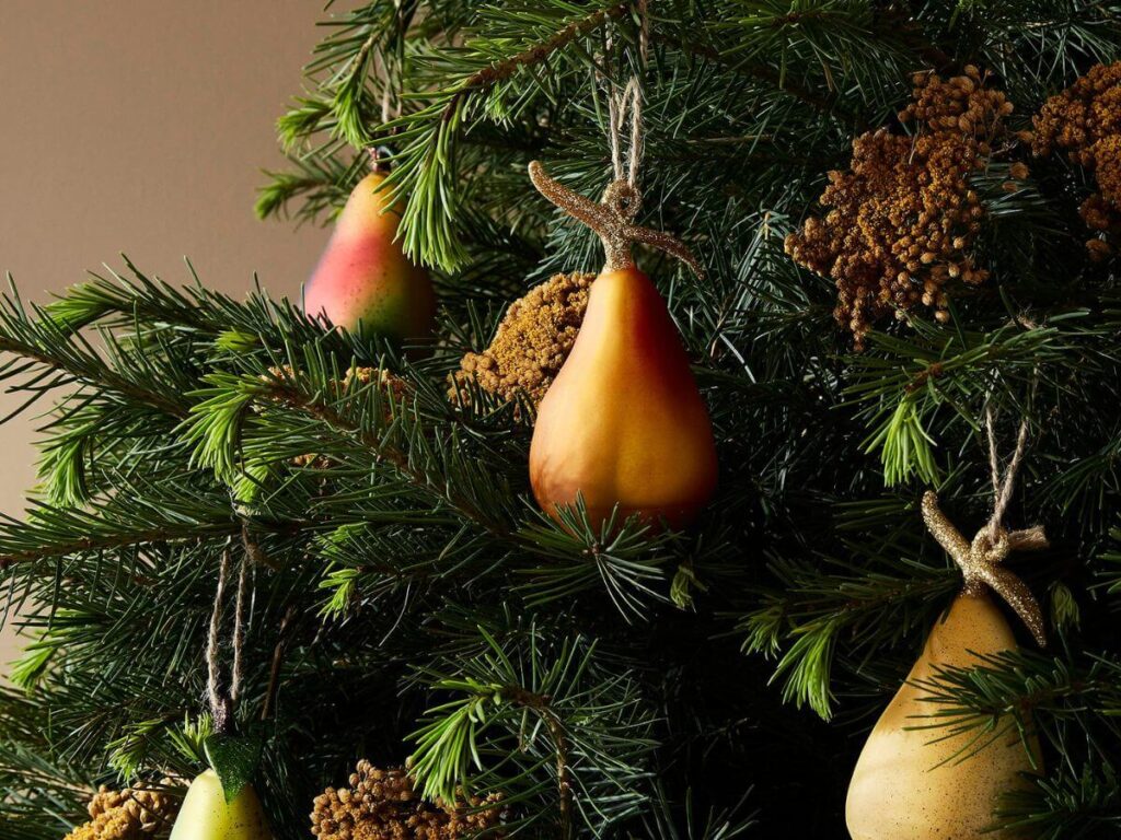 A real Christmas tree with gold pears hanging from it and pine cones