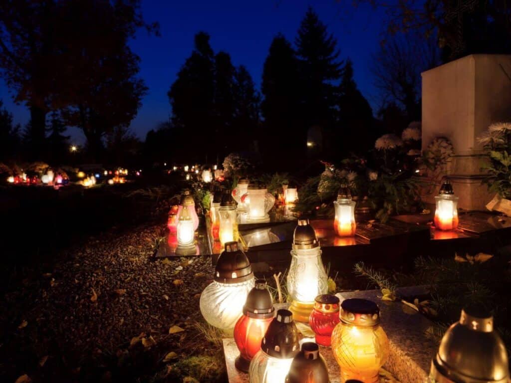 A collection of lanterns lit at night in a graveyard in France