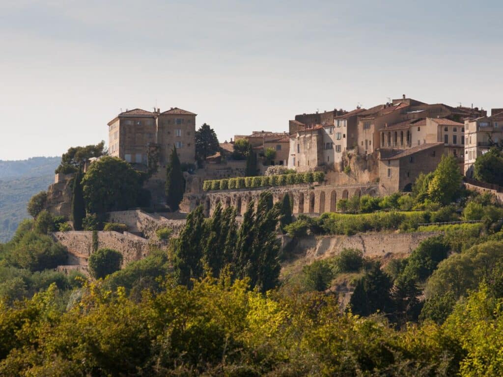 Perched atop a hill, the historic village of Lauris in the Luberon region is framed by lush greenery. The stone buildings with their sun-kissed facades and terraced gardens present a timeless tableau that whispers stories of the Provencal past under a gentle sky.