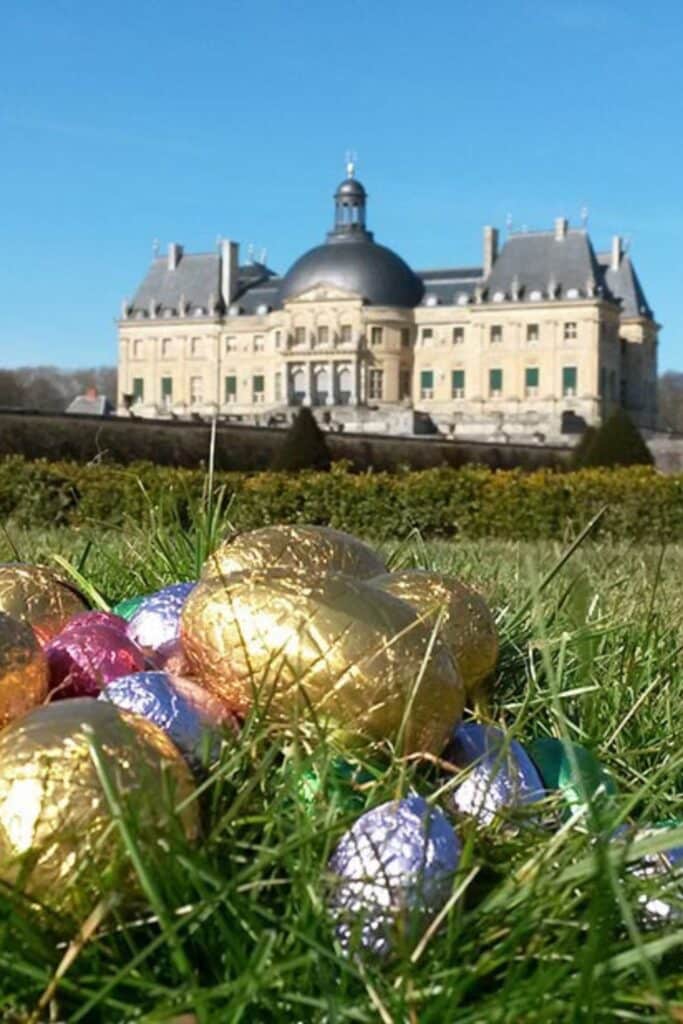 Close-up of shiny, foil-wrapped Easter eggs hidden in the grass during a traditional French Easter egg hunt, known as "La Chasse aux Œufs."