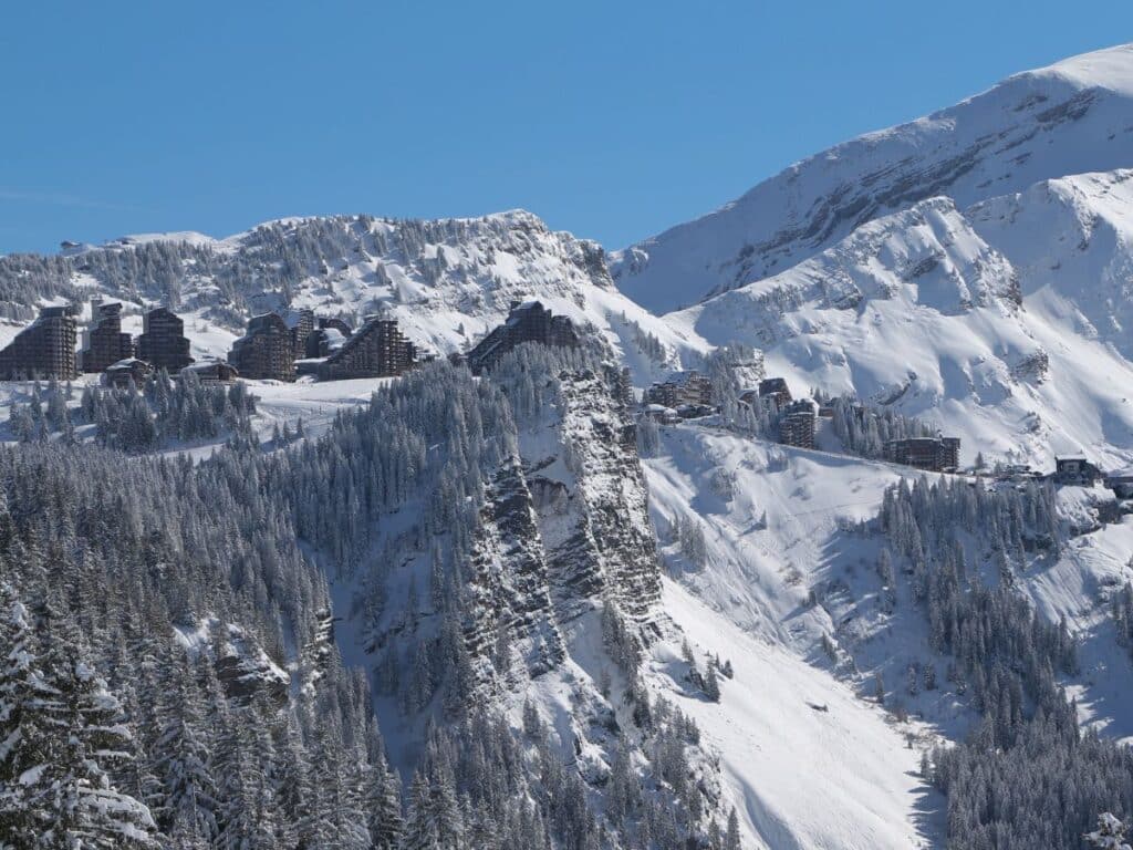 Snow-covered ski resort nestled among alpine peaks under a clear blue sky.