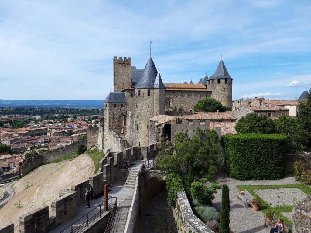 The expansive medieval fortress of Carcassonne Castle stands atop a hill, overlooking the surrounding French landscape, highlighting its reputation as one of the largest medieval fortresses in the world.