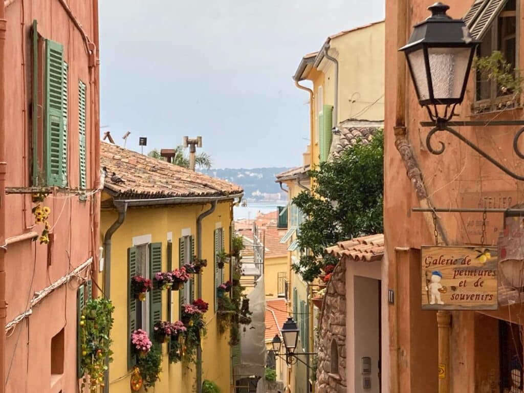 Narrow Mediterranean alley with colorful houses and a glimpse of the sea.