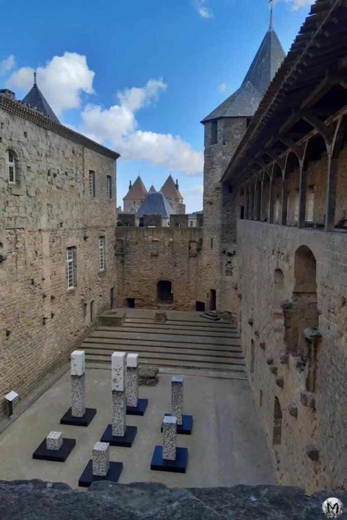 A courtyard view inside Carcassonne Castle, featuring modern art installations among ancient stone walls, connecting the past with contemporary culture."
