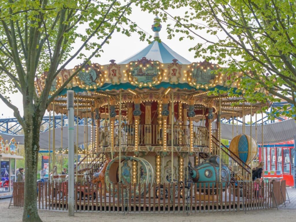 Carousel nestled among trees with intricate designs and soft lighting in a festive area.