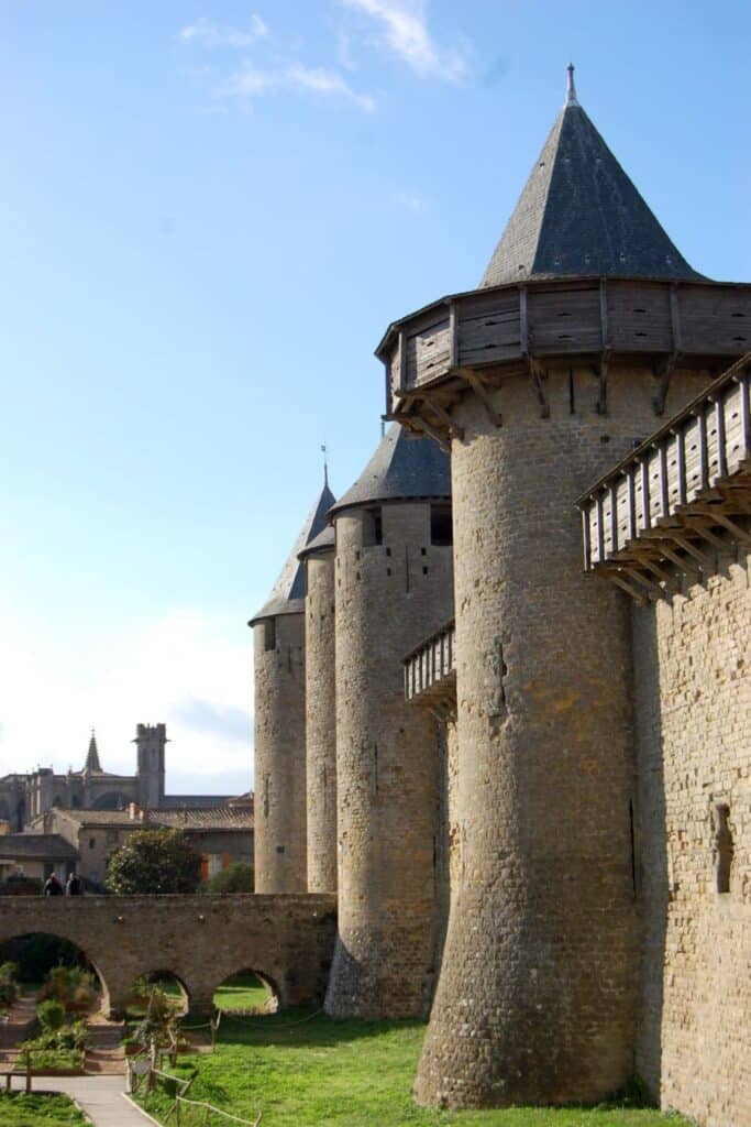 An imposing view of Carcassonne Castle's towers and ramparts against a clear sky, highlighting the fortified structure's resilience through its turbulent history.