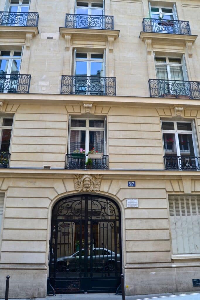 Limestone Paris building with ornate iron gate.