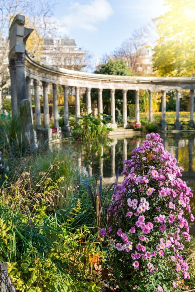 Autumn blooms and a colonnade reflected in a pond.