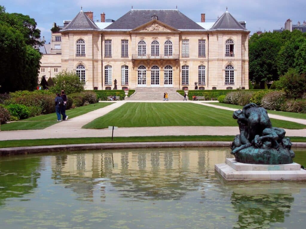 Formal gardens and a classic French mansion with a statue.