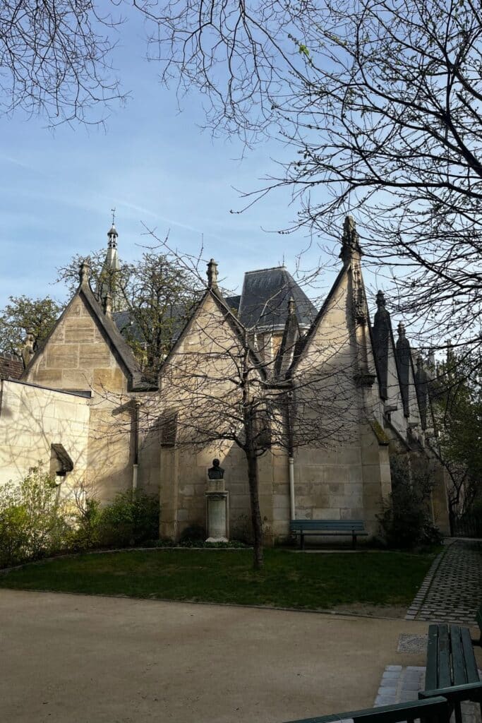 Gothic chapel with flying buttresses, in serene park setting.