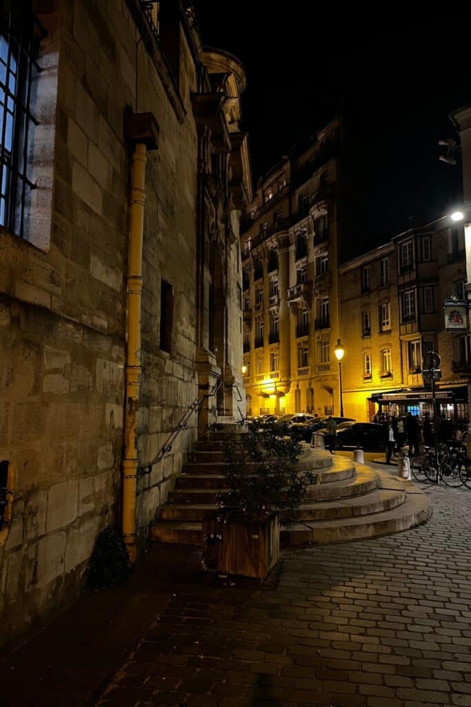 Cobblestone alley and bistro in Paris at night.