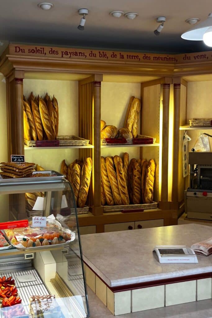 A bakery's golden baguettes on wooden shelves.