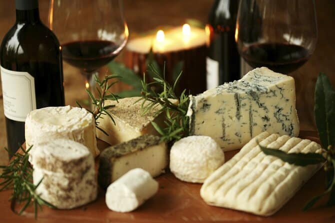 Assorted cheese board with herbs, candles, and wine in soft focus.