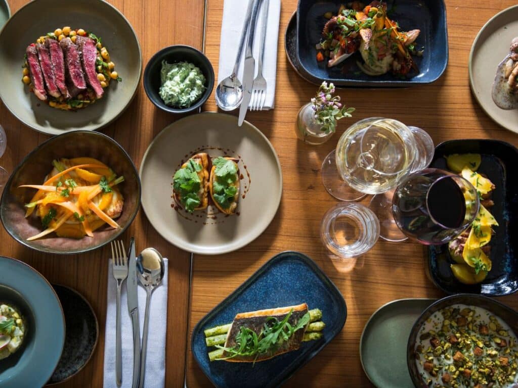 Overhead view of a rustic table set with gourmet dishes and wine.