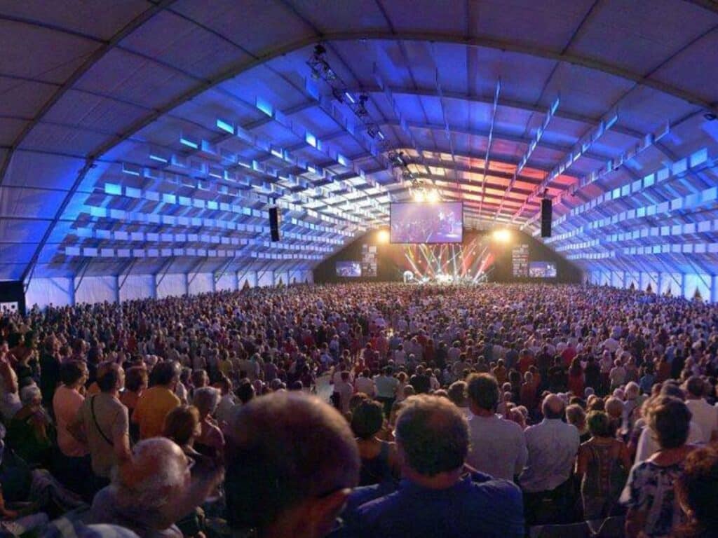 Jazz in Marciac music festival in a big tent with hundreds of people watching a concert at night.