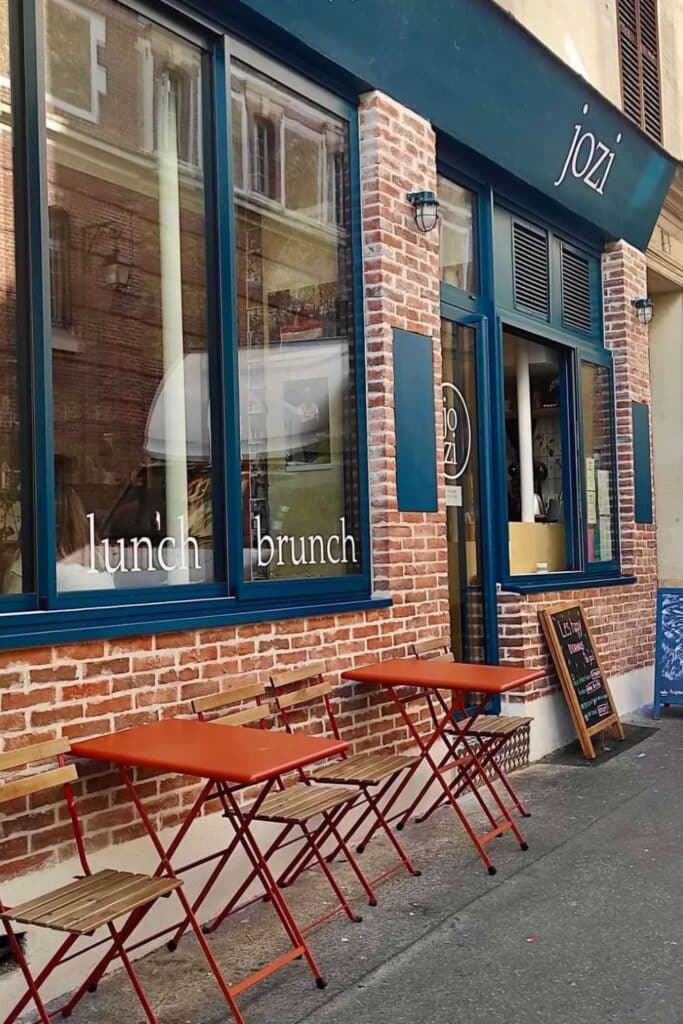 Cozy street-side café with red tables, brick wall, and 'lunch brunch' window text.