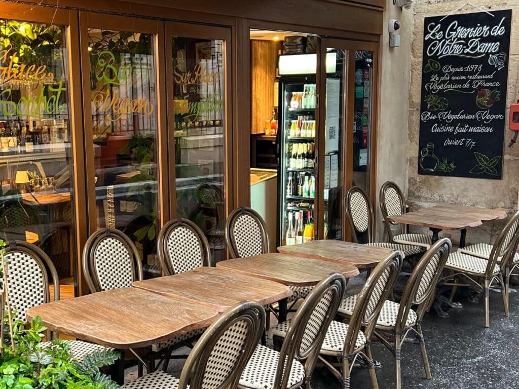 Rustic outdoor vegan bistro with wicker chairs and greenery.