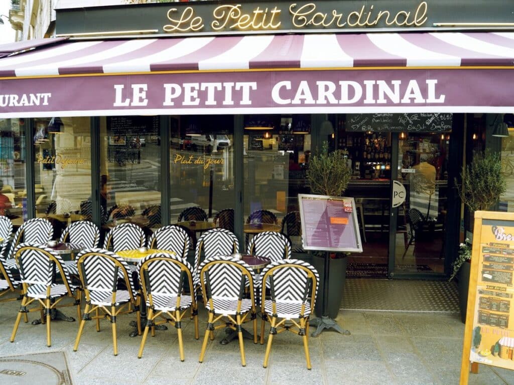 Parisian café with striking black and white chairs and purple awning on a bustling street.