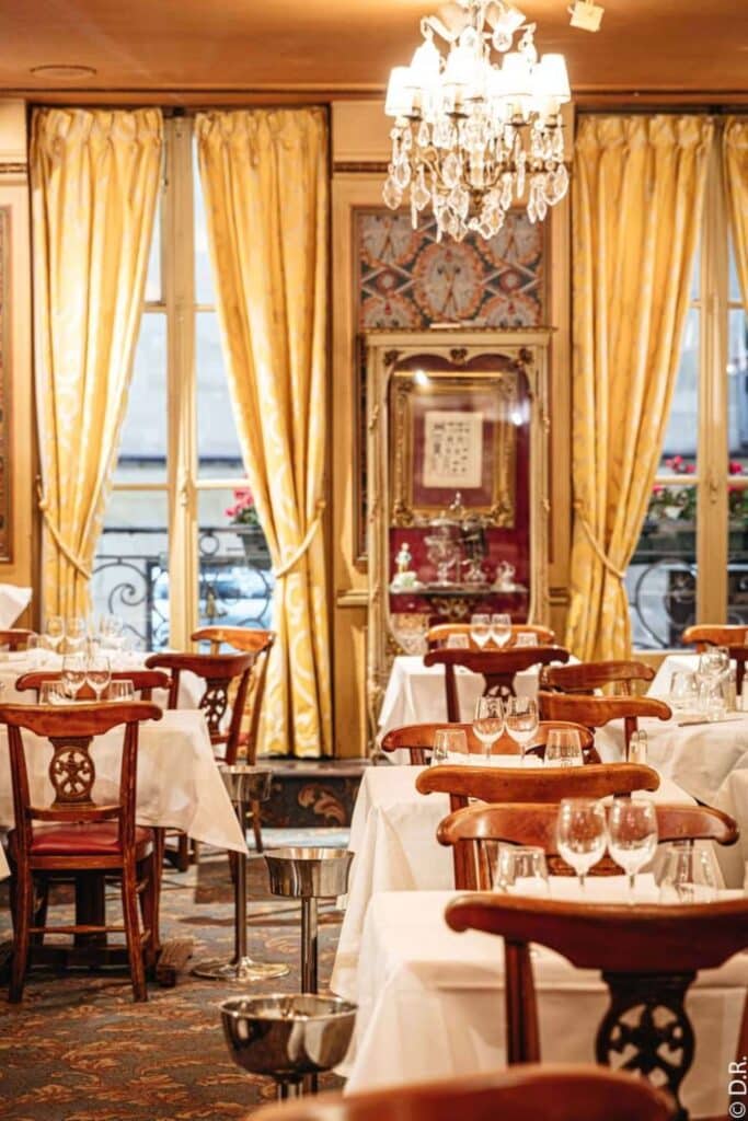 Classic French bistro interior with chandelier and gold drapes.