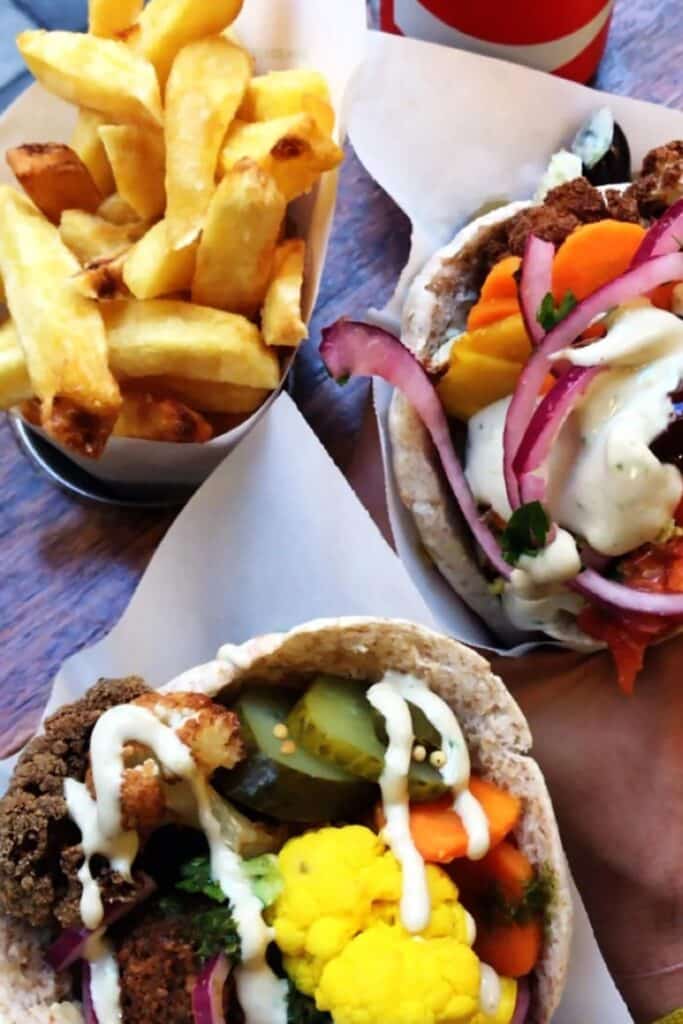 Close-up of a colorful vegan pita and fries.