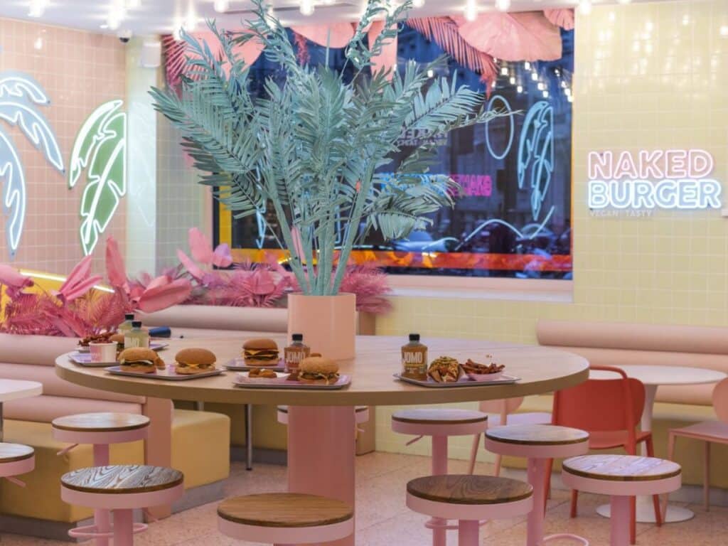 Trendy vegan burger café with neon signs and pastel decor.