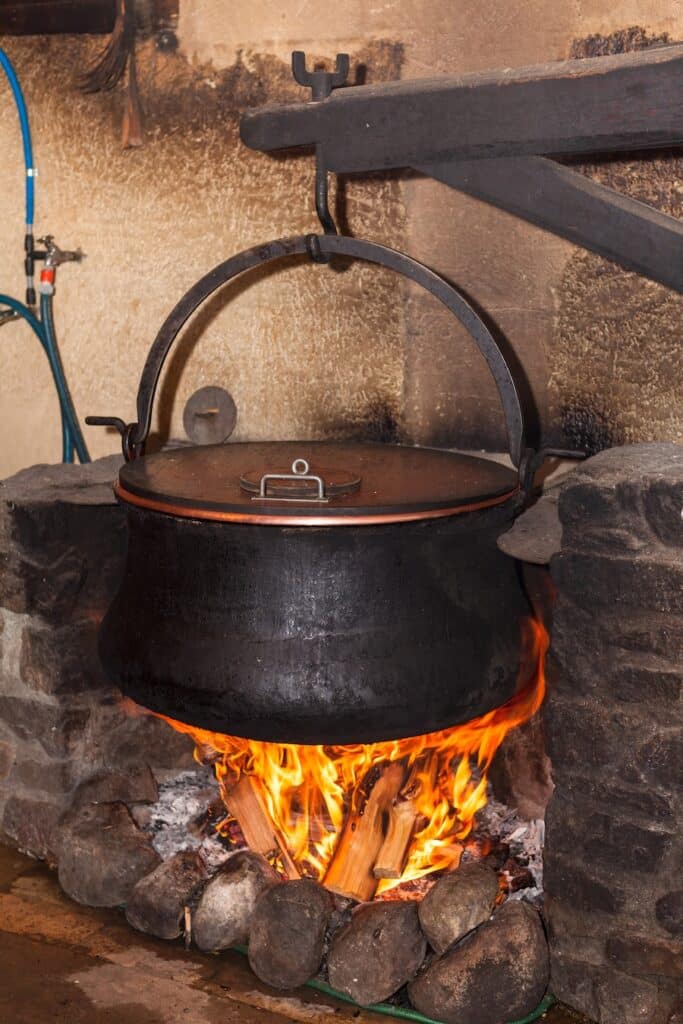 An old pot over a fireplace cooking Boeuf Bourguignon