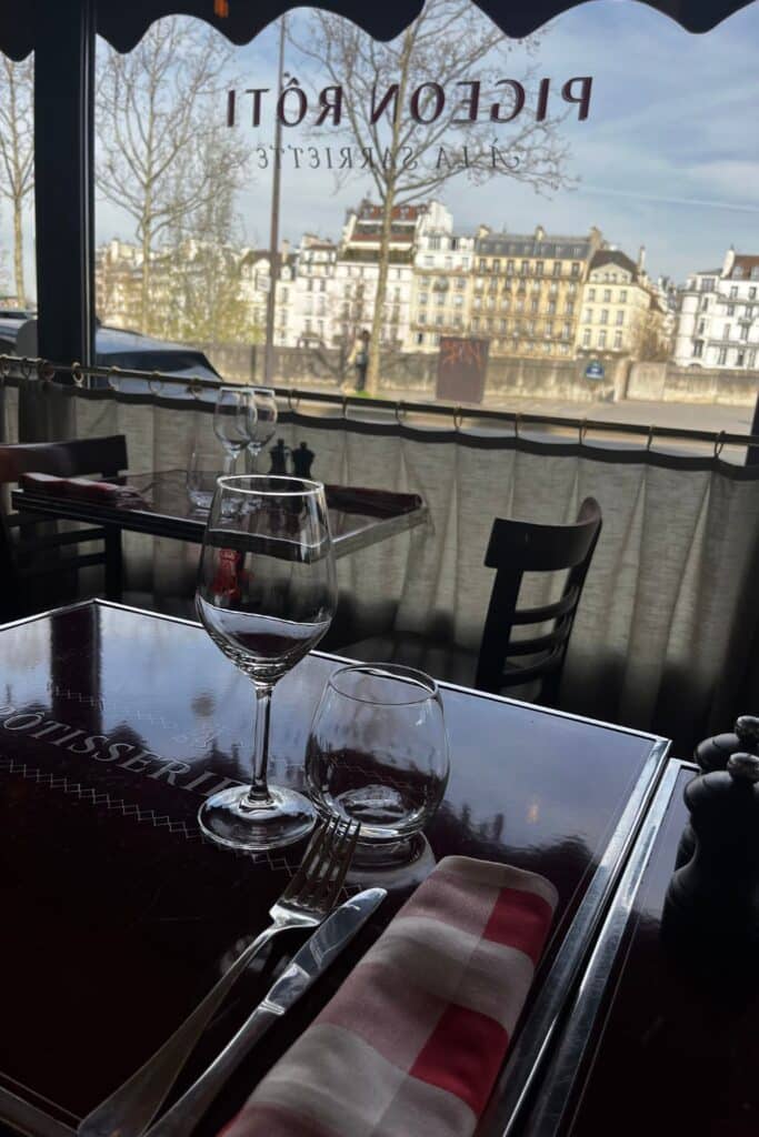 Table by a window with city view, wine glasses, and elegant tableware.