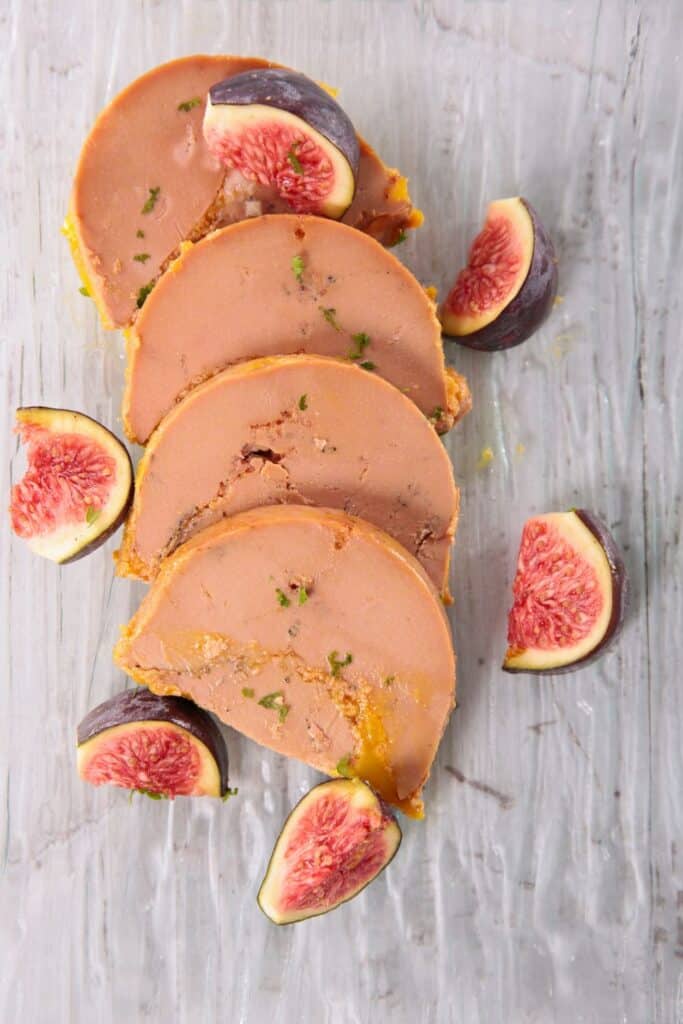 A collection of fresh figs, including both whole and halved, displayed on a rustic wooden surface.