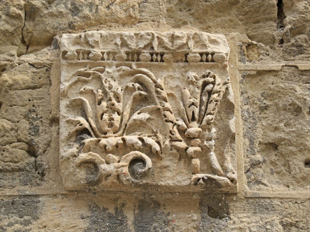A close-up of a detailed stone carving found on a historic wall in Narbonne, France, illustrating ornate Roman-era designs that capture the artistic and architectural history of the region.