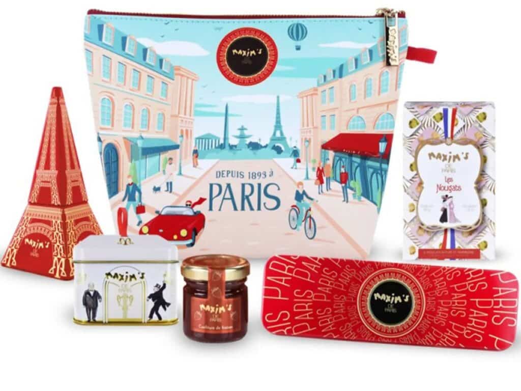 A colorful Paris-themed gift set with an Eiffel Tower cutout, gourmet jam, nougat, and a decorative zip pouch printed with a whimsical Parisian street scene.