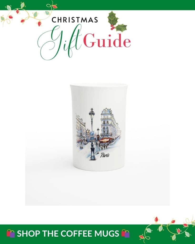 Agraphic for the "Christmas Gift Guide" shows a white mug with a detailed illustration of a Paris street scene, including classic Parisian architecture, street lamps, and the word "Paris" beneath the artwork. A "Shop the Coffee Mugs" banner at the bottom invites viewers to explore.