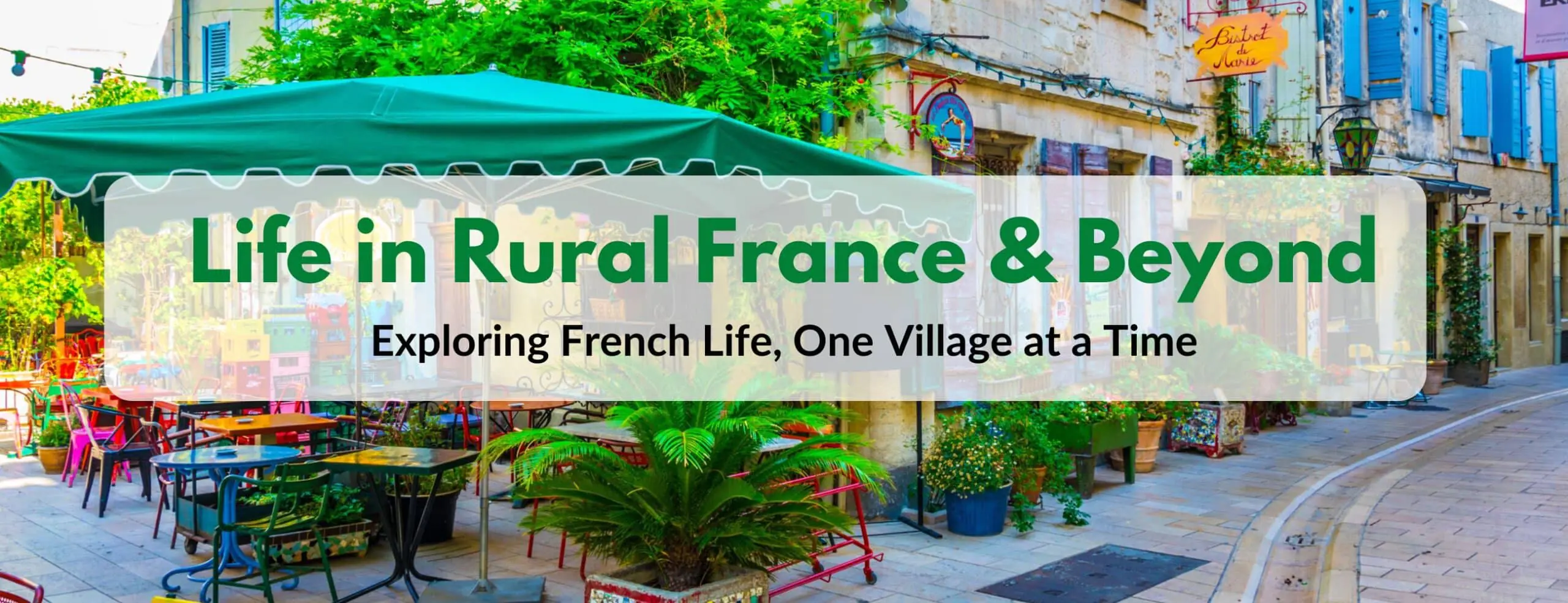 Colorful outdoor cafe scene in a quaint French village, featuring a green canopy, vibrant chairs and tables, and lush plants. The background includes stone buildings with blue shutters and signs, evoking a charming and relaxed rural atmosphere. Overlaid text reads: 'Life in Rural France & Beyond - Exploring French Life, One Village at a Time.