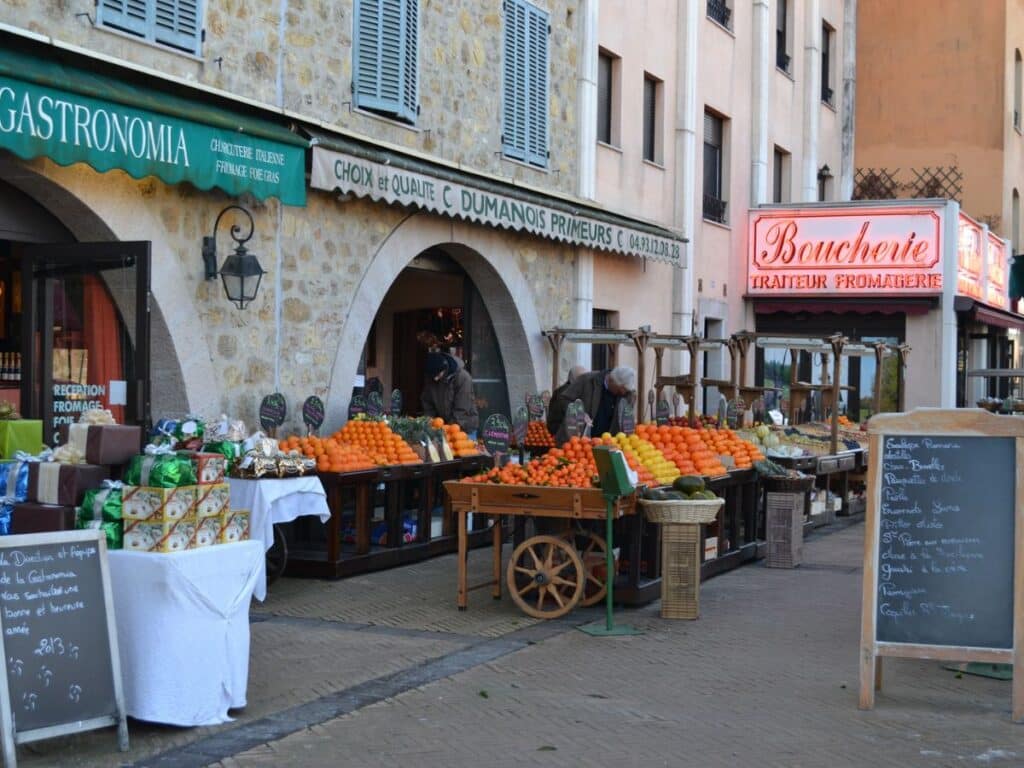 A picturesque French street with outdoor market stalls under colorful awnings, showcasing the vibrant lifestyle awaiting Americans moving to France.