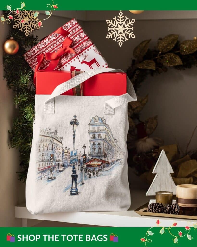 A Parisian street scene tote bag placed in a holiday setting with festive gift boxes, showing a classic Paris street with charming buildings and street lamps, framed by Christmas ornaments and greenery.