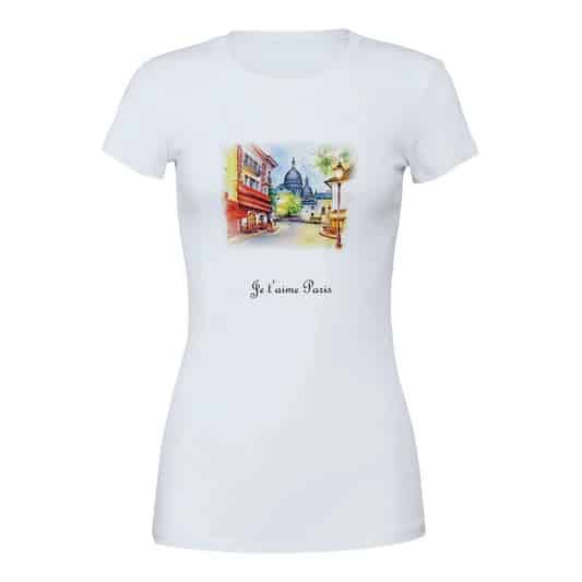 A white t-shirt with a watercolor-style illustration of a quaint Paris street, leading towards the domed Sacré-Cœur Basilica. The text "Je t'aime Paris" beneath the image adds a touch of French affection to the design.