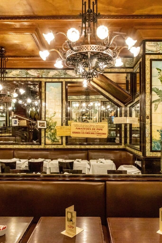 The ornate, vintage interior of Brasserie Lipp, a classic Paris café, with intricate chandeliers, mirrors, and tiled walls exuding old-world charm.