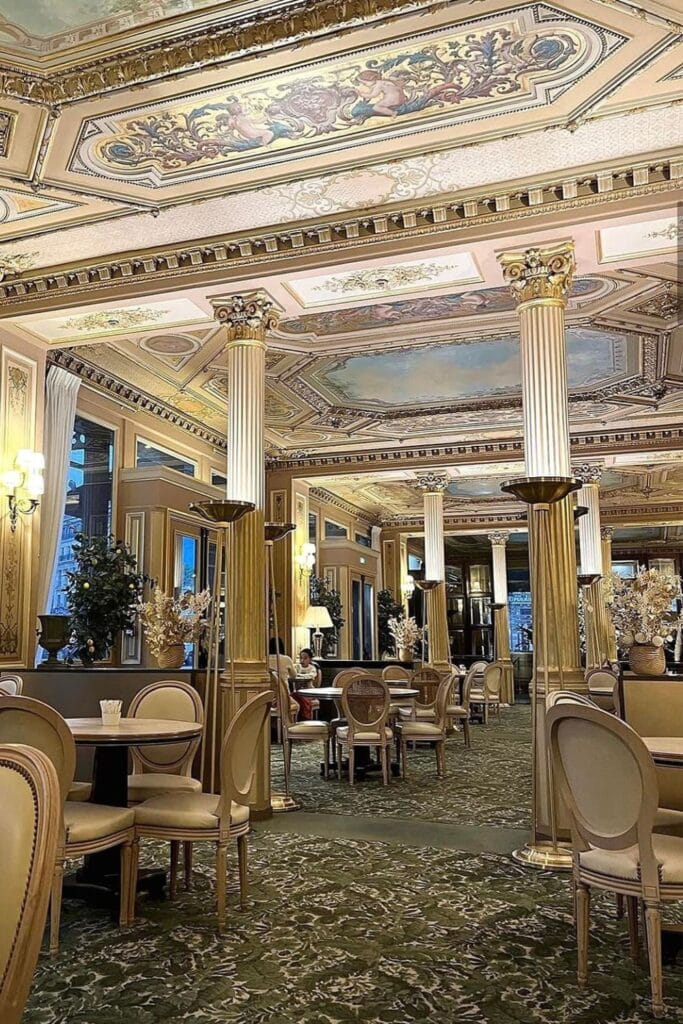 The opulent interior of Café de la Paix, with gilded columns, ornate ceilings, and elegant tables set in a historic Parisian dining space.
