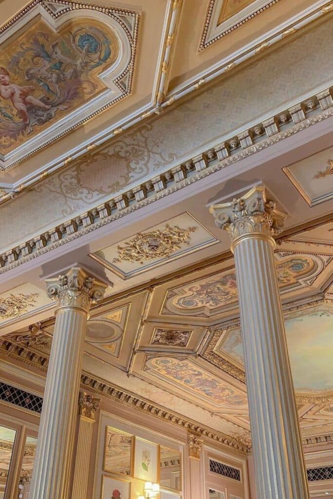 The grand ceiling of Café de la Paix, featuring intricate gold detailing, painted frescoes, and classical architecture.