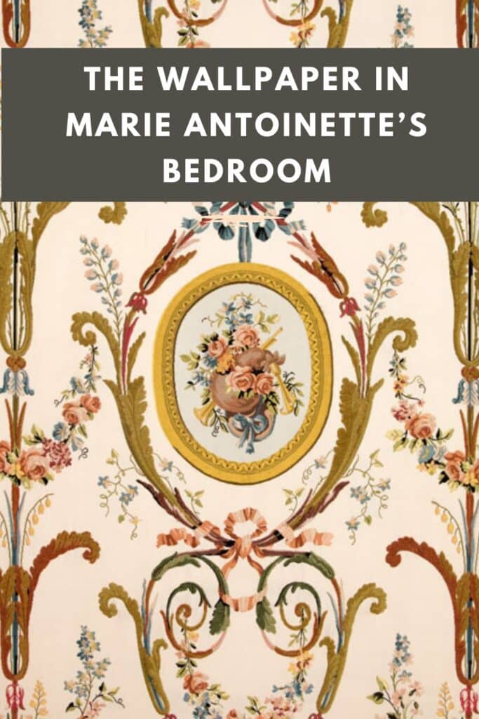A close-up of ornate wallpaper featuring intricate floral patterns, golden scrollwork, and a central medallion with a painted bouquet of roses.