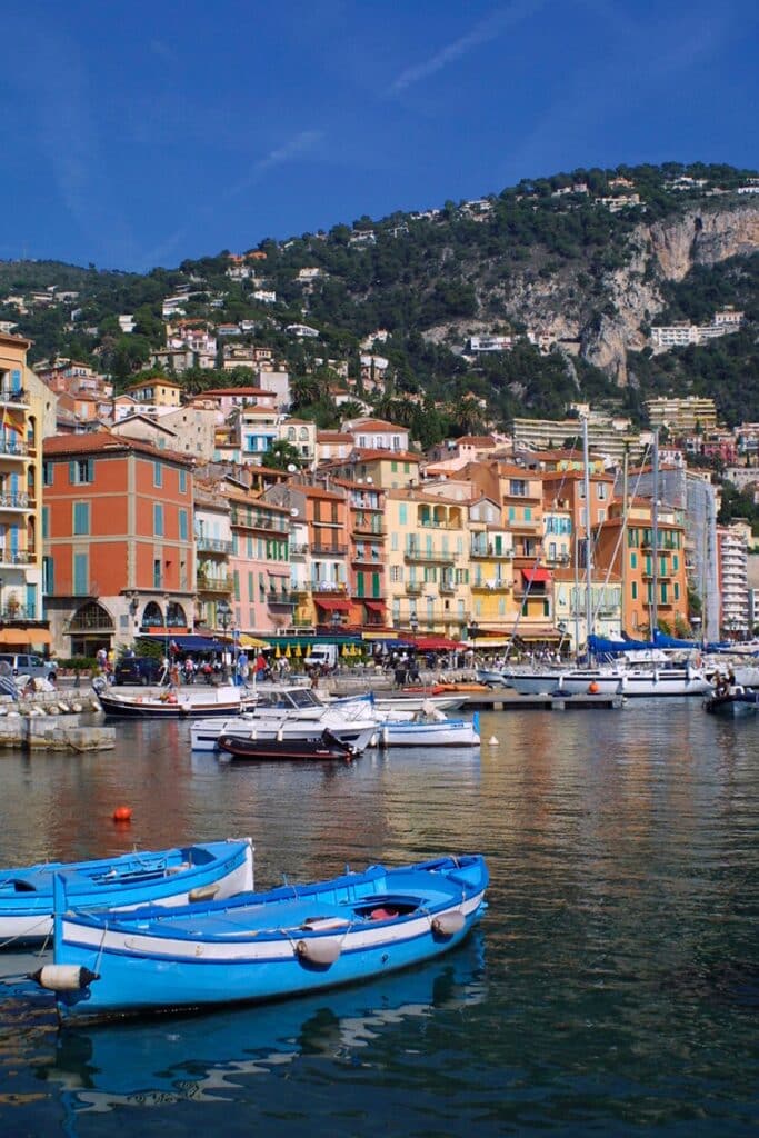 A colorful harbor in Villefranche-sur-Mer with traditional fishing boats and vibrant waterfront buildings, a perfect Instagram spot.