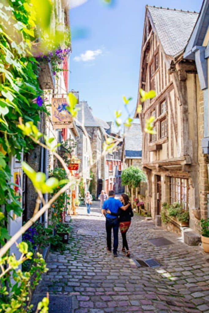 Romantic cobblestone streets in Dinan, flanked by historic timber-framed houses and vibrant flower displays.