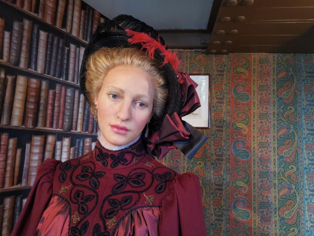 A wax figure of a woman dressed in 19th-century attire, representing Janine, the granddaughter of Gustave Eiffel, inside the Eiffel Tower Apartment.