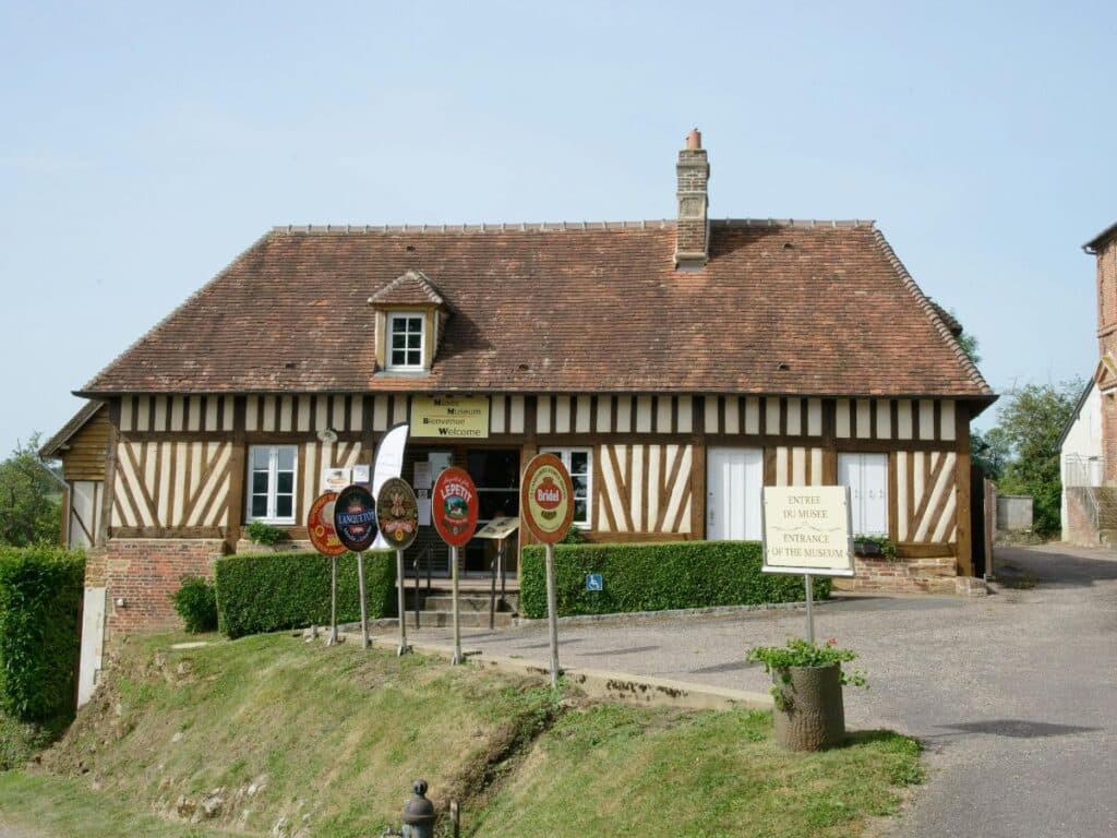 A charming half-timbered building with signs welcoming visitors to the Maison du Camembert Museum, dedicated to the history of camembert cheese.