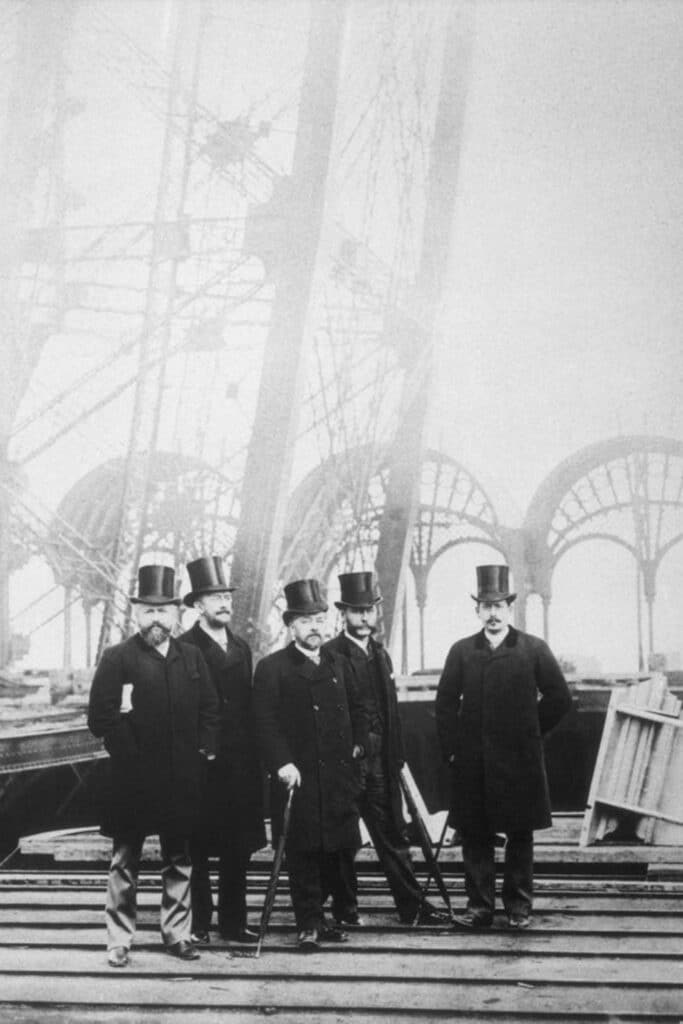 A black-and-white photograph capturing Gustave Eiffel and his team during the construction of the Eiffel Tower, where the famous Eiffel Tower Apartment was later built.