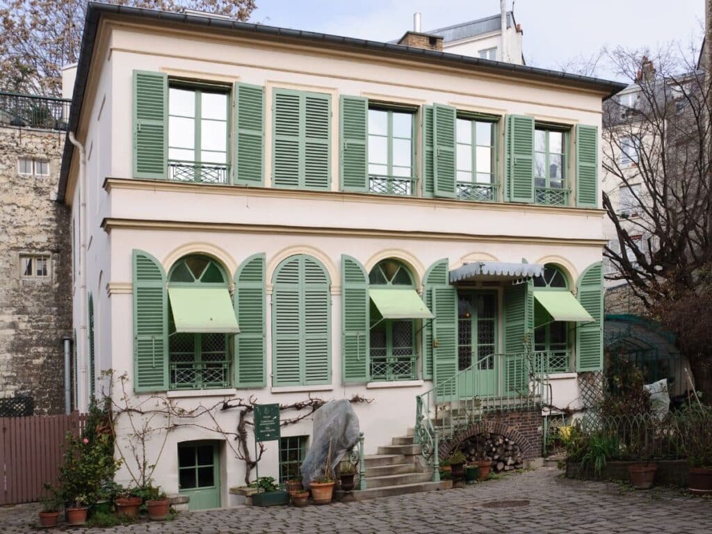 The pastel-toned Musée de la Vie Romantique, once the home of Ary Scheffer, one of the famous residents of Montmartre. The charming house with green shutters and potted plants showcases the neighborhood’s romantic 19th-century vibe.