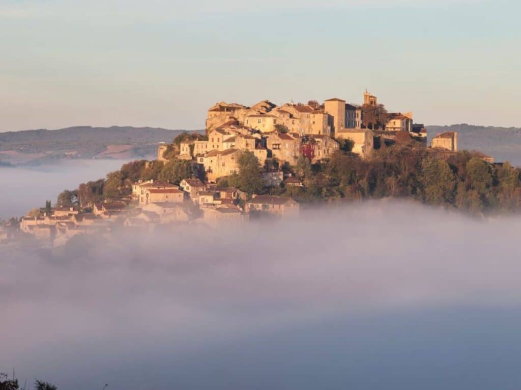 A hilltop village bathed in golden light floats above a sea of morning mist, showcasing Cordes-sur-Ciel as one of the most ethereal storybook towns in France.