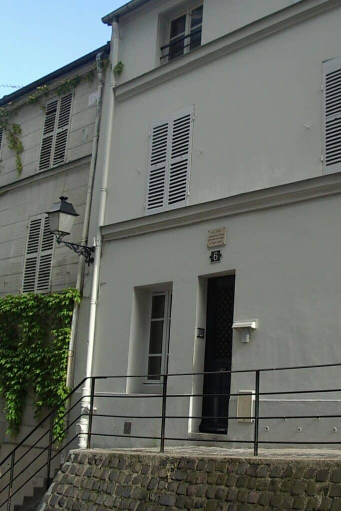 A quiet facade of Erik Satie’s former residence in Montmartre, marked with a commemorative plaque above the door. This modest white building reflects the understated lifestyle of one of Montmartre’s famous residents in the early 20th century.